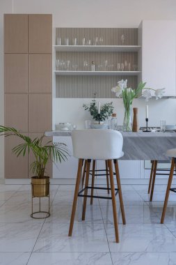 Yakın manzaralı mutfak, yemek masası ve minimalist hafif bar tabureleri yumuşak pastel bej renkli modern geniş bir stüdyo dairesinin lüks tasarımı.