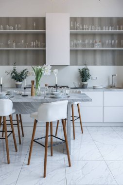 Yakın manzaralı mutfak, yemek masası ve minimalist hafif bar tabureleri yumuşak pastel bej renkli modern geniş bir stüdyo dairesinin lüks tasarımı.