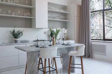 Yakın manzaralı mutfak, yemek masası ve minimalist hafif bar tabureleri yumuşak pastel bej renkli modern geniş bir stüdyo dairesinin lüks tasarımı.