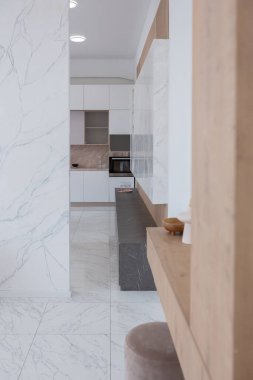 Minimalist tarzda, mermer süslemeli ve kocaman pencereli, modern bir apartman dairesi tasarımı. Mutfakta ve oturma odasında gün ışığı.