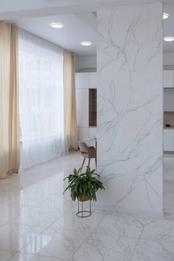 Minimalist tarzda, mermer süslemeli ve kocaman pencereli, modern bir apartman dairesi tasarımı. Mutfakta ve oturma odasında gün ışığı.