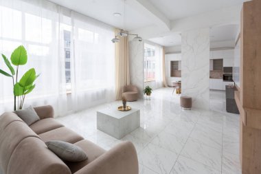 Minimalist tarzda, mermer süslemeli ve kocaman pencereli, modern bir apartman dairesi tasarımı. Mutfakta ve oturma odasında gün ışığı.