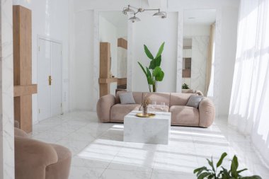 Hafif bej mobilyalı oturma odası. Lüks bir iç tasarım. Minimalist tarzda, mermer süslemeli ve kocaman pencereli modern bir daire. İçeride gün ışığı.