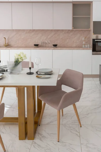 stock image stylish kitchen and a set dining table in a light luxury interior design of a modern apartment in a minimalist style with marble trim and huge windows. daylight inside.