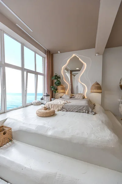 卧室的内部是一个大窗户旁边的巴厘风格的 可以看到令人敬畏的海景 床后面是一面带有Led照明的弧形镜子 — 图库照片