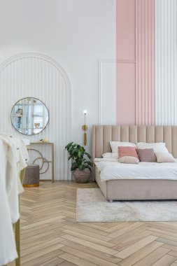 Güneşli bir günde şık, modern bir tasarımı olan geniş, açık planlı bir apartmanın penceresinin yanındaki yatak odasında yumuşak bir yatak.