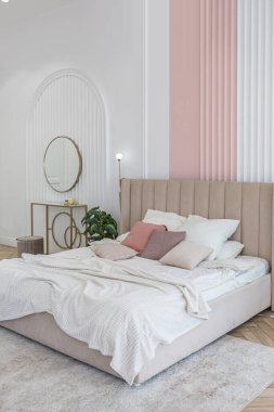 Güneşli bir günde şık, modern bir tasarımı olan geniş, açık planlı bir apartmanın penceresinin yanındaki yatak odasında yumuşak bir yatak.