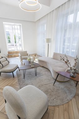 Yaratıcı kahve masası ve şık döşenmiş mobilyalar güneşli bir günde şık ve modern bir tasarıma sahip geniş, açık planlı bir dairede oturma odasında.