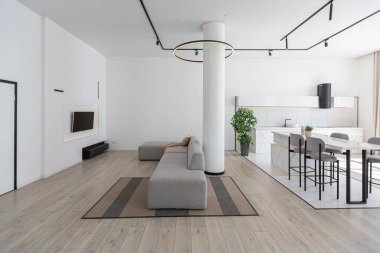 Güneşli bir günde mermer süslemeli pahalı bir evin minimalist modern lüks tasarımı. Alçılı beyaz duvarlar, parke, dekoratif ışıklandırma ve içeride kimse yok.