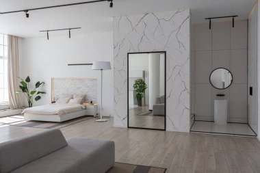 Güneşli bir günde mermer süslemeli pahalı bir evin minimalist modern lüks tasarımı. Alçılı beyaz duvarlar, parke, dekoratif ışıklandırma ve içeride kimse yok.