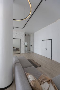 Güneşli bir günde mermer süslemeli pahalı bir evin minimalist modern lüks tasarımı. Alçılı beyaz duvarlar, parke, dekoratif ışıklandırma ve içeride kimse yok.