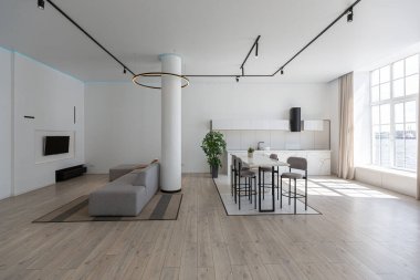 Güneşli bir günde mermer süslemeli pahalı bir evin minimalist modern lüks tasarımı. Alçılı beyaz duvarlar, parke, dekoratif ışıklandırma ve içeride kimse yok.