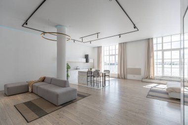 Güneşli bir günde mermer süslemeli pahalı bir evin minimalist modern lüks tasarımı. Alçılı beyaz duvarlar, parke, dekoratif ışıklandırma ve içeride kimse yok.