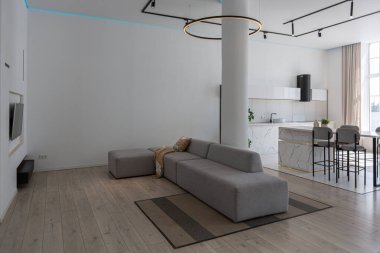 Güneşli bir günde mermer süslemeli pahalı bir evin minimalist modern lüks tasarımı. Alçılı beyaz duvarlar, parke, dekoratif ışıklandırma ve içeride kimse yok.