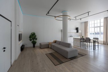 Güneşli bir günde mermer süslemeli pahalı bir evin minimalist modern lüks tasarımı. Alçılı beyaz duvarlar, parke, dekoratif ışıklandırma ve içeride kimse yok.