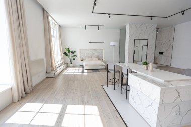 Güneşli bir günde mermer süslemeli pahalı bir evin minimalist modern lüks tasarımı. Alçılı beyaz duvarlar, parke, dekoratif ışıklandırma ve içeride kimse yok.