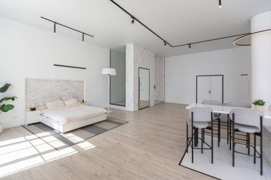 Güneşli bir günde mermer süslemeli pahalı bir evin minimalist modern lüks tasarımı. Alçılı beyaz duvarlar, parke, dekoratif ışıklandırma ve içeride kimse yok.