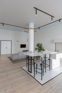 Güneşli bir günde mermer süslemeli pahalı bir evin minimalist modern lüks tasarımı. Alçılı beyaz duvarlar, parke, dekoratif ışıklandırma ve içeride kimse yok.