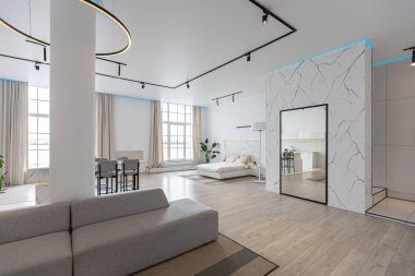 Güneşli bir günde mermer süslemeli pahalı bir evin minimalist modern lüks tasarımı. Alçılı beyaz duvarlar, parke, dekoratif ışıklandırma ve içeride kimse yok.
