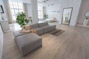 Güneşli bir günde mermer süslemeli pahalı bir evin minimalist modern lüks tasarımı. Alçılı beyaz duvarlar, parke, dekoratif ışıklandırma ve içeride kimse yok.