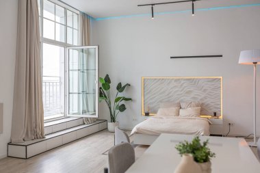 Güneşli bir günde mermer süslemeli pahalı bir evin minimalist modern lüks tasarımı. Alçılı beyaz duvarlar, parke, dekoratif ışıklandırma ve içeride kimse yok.