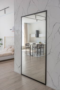 Güneşli bir günde mermer süslemeli pahalı bir evin minimalist modern lüks tasarımı. Alçılı beyaz duvarlar, parke, dekoratif ışıklandırma ve içeride kimse yok.