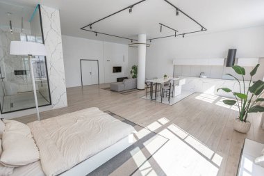 Güneşli bir günde mermer süslemeli pahalı bir evin minimalist modern lüks tasarımı. Alçılı beyaz duvarlar, parke, dekoratif ışıklandırma ve içeride kimse yok.