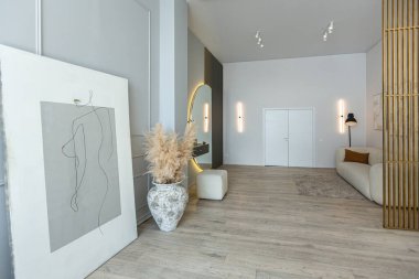 Modern tasarım, aydınlık duvarlar ve ahşap zemin içinde parlak, açık planlı bir daire. Güzel bir vazosu ve yuvarlak aynası olan şık bir koridor.