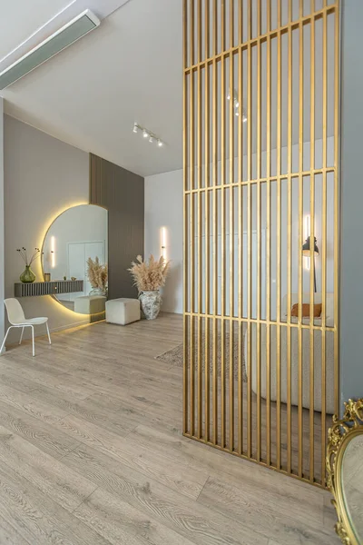 bright open-plan apartment in a modern design, light walls and wooden floor. stylish entrance hall with a beautiful vase and a round mirror and a sofa for guests