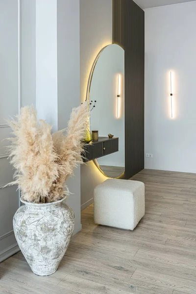 bright open-plan apartment in a modern design, light walls and wooden floor. stylish hallway with a beautiful vase and a round mirror