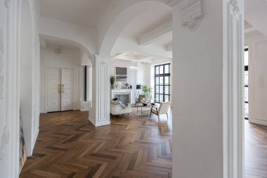 Pahalı, parlak bir iç mekan tarihi bir malikanede büyük bir oturma odası kemerli kemerler, sütunlar ve süslemelerle süslenmiş beyaz duvarlar..