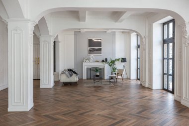 Pahalı, parlak bir iç mekan tarihi bir malikanede büyük bir oturma odası kemerli kemerler, sütunlar ve süslemelerle süslenmiş beyaz duvarlar..