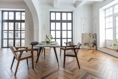 Pahalı bir iç mekanda, şık bir yemek masasının manzarası tarihi bir malikanede kemerli kemerler, kolonlar ve süslemelerle süslenmiş beyaz duvarlarla süslenmiş büyük bir oturma odası..