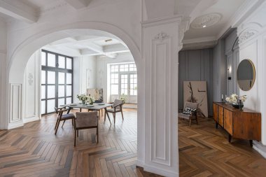 Pahalı, parlak bir iç mekan tarihi bir malikanede büyük bir oturma odası kemerli kemerler, sütunlar ve süslemelerle süslenmiş beyaz duvarlar..