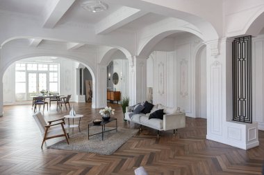 Pahalı, parlak bir iç mekan tarihi bir malikanede büyük bir oturma odası kemerli kemerler, sütunlar ve süslemelerle süslenmiş beyaz duvarlar..