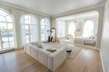 Büyük panoramik pencereli, güneşli, rahat, parlak bir daire. Beyaz, bej renkli, şömineli ve koltuklu bir yatak odası. Kütük sehpası ve büyük beyaz kanepesi olan şık bir oturma odası.