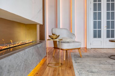 Şöminesi, dekoratif panelleri ve ışığı yumuşak gün ışığında, insanlar olmadan, pastel renklerde olan modern bir oturma odasının içi..