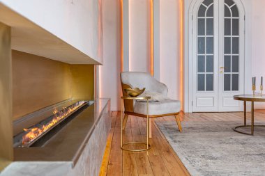 Şöminesi, dekoratif panelleri ve ışığı yumuşak gün ışığında, insanlar olmadan, pastel renklerde olan modern bir oturma odasının içi..