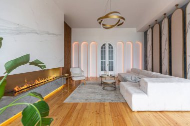 Şöminesi, dekoratif panelleri ve ışığı yumuşak gün ışığında, insanlar olmadan, pastel renklerde olan modern bir oturma odasının içi..