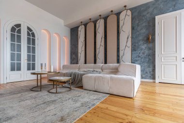 Şöminesi, dekoratif panelleri ve ışığı yumuşak gün ışığında, insanlar olmadan, pastel renklerde olan modern bir oturma odasının içi..
