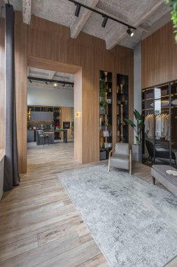 Yüksek tavan tavanı, ahşap dekorasyonu ve gri duvarları olan büyük, modern, geniş bir dairede ışık saçan şık bir soyunma odası.