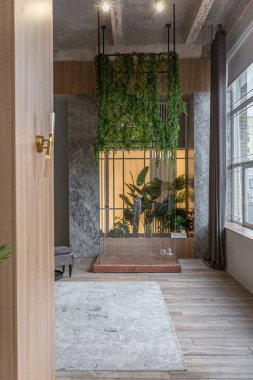 Çatı katı tarzı tavanları, ahşap süslemeleri ve gri duvarları olan büyük, modern, geniş bir dairede orman tarzı ayrı bir duş.