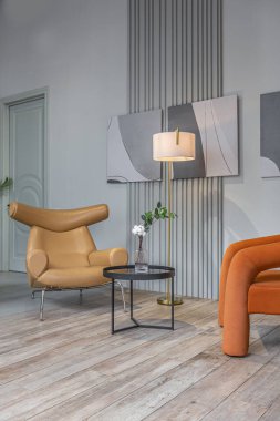 Yüksek tavan tavanı, ahşap süslemesi ve gri duvarları olan büyük, modern geniş dairede iki yumuşak şık koltuğu olan oturma alanı.