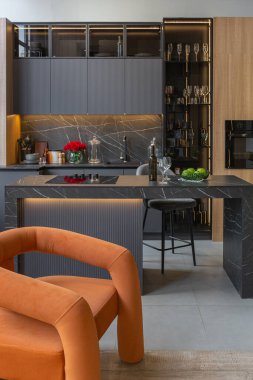 Ahşap dekore edilmiş karanlık mutfak alanı, aşçılık adası, yüksek tavan tavanı, ahşap süslemesi ve gri duvarları olan büyük, modern geniş bir daire.