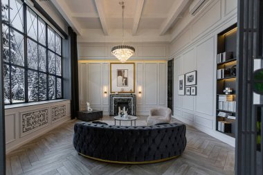 Parlak, lüks bir dağ evi. Kış ormanlarının göz kamaştırıcı manzarası panoramik pencerelerden beyaz duvarlar, süsler, şömine, iş ve gün boyu insan olmadan oturma alanı.