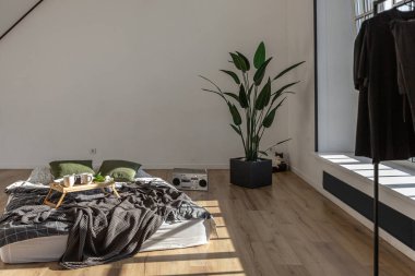 Minimalist stil. Tavanda penceresi ve güneş ışınları olan, bembeyaz, sade yatak odası.