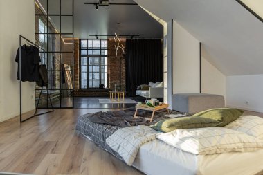 Minimalist stil. Tavanda penceresi ve güneş ışınları olan, bembeyaz, sade yatak odası.