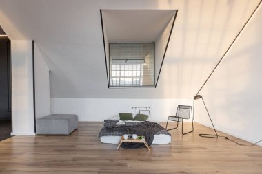 Minimalist stil. Tavanda penceresi ve güneş ışınları olan, bembeyaz, sade yatak odası.
