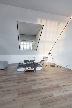 Minimalist stil. Tavanda penceresi ve güneş ışınları olan, bembeyaz, sade yatak odası.