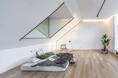 Minimalist stil. Tavanda penceresi ve güneş ışınları olan, bembeyaz, sade yatak odası.